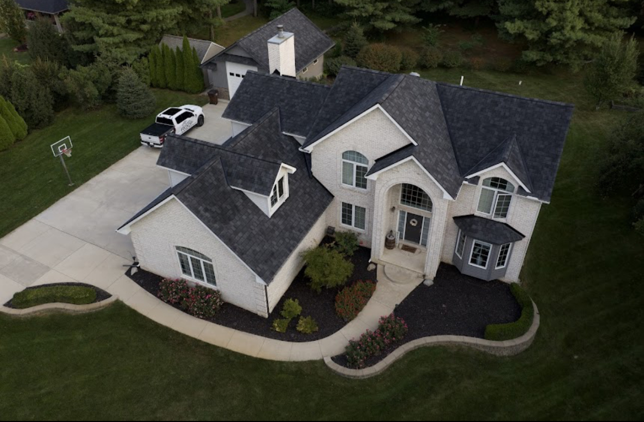 Aerial view of a large brick home with a completed charcoal architectural shingle roof. Roofing work by Alba Pro Construction serving Wyckoff, NJ.