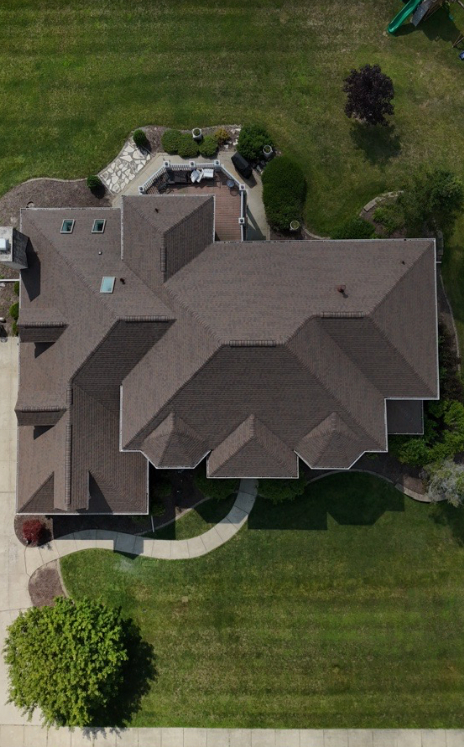 Aerial view of a large home with a completed brown architectural shingle roof across multiple hips and valleys. Roofing work by Alba Pro Construction serving Tenafly, NJ.