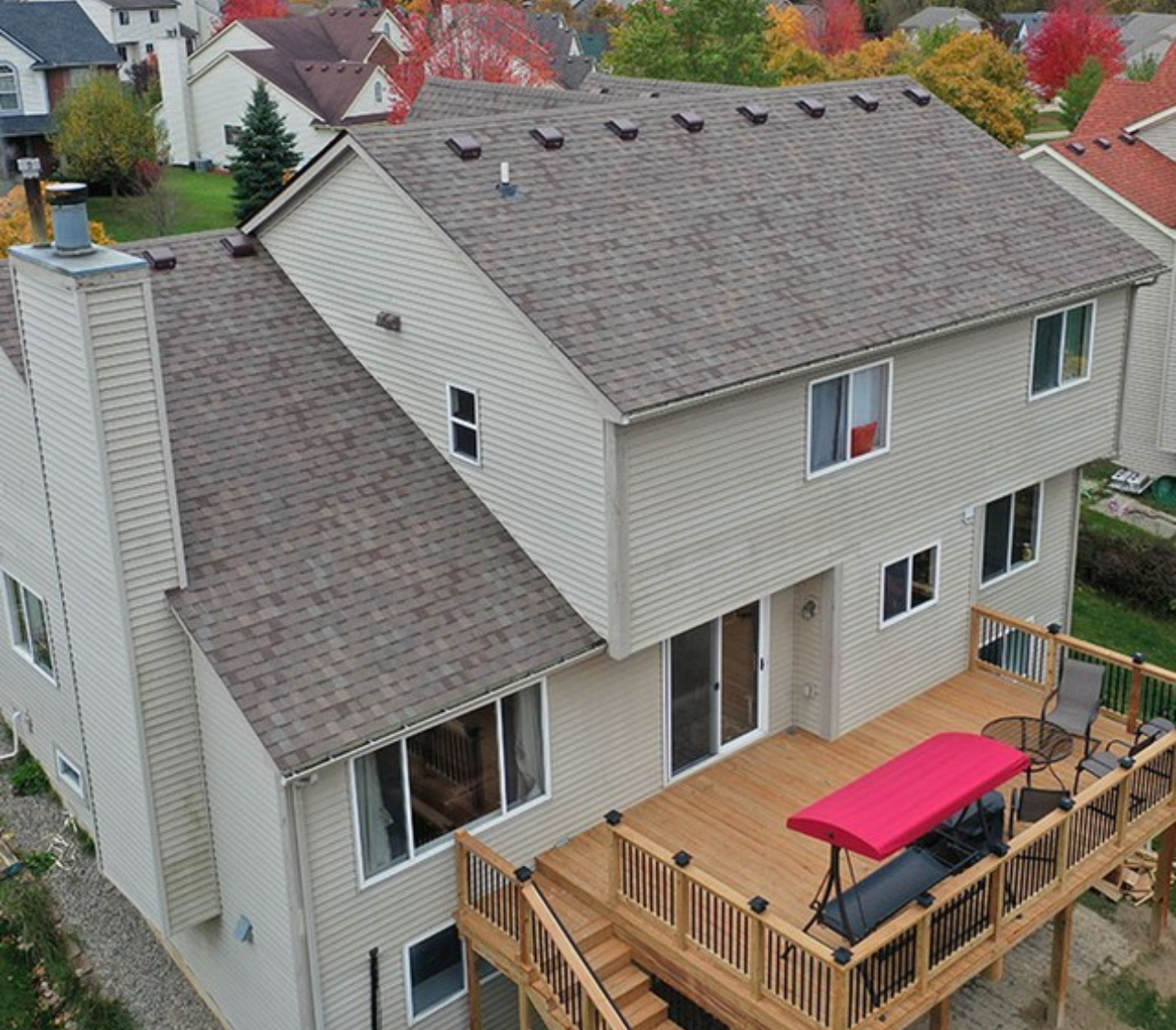Aerial view of a completed architectural shingle roof with new ridge vents on a two-story home with a wood deck. Roofing work by Alba Pro Construction serving Totowa, NJ.