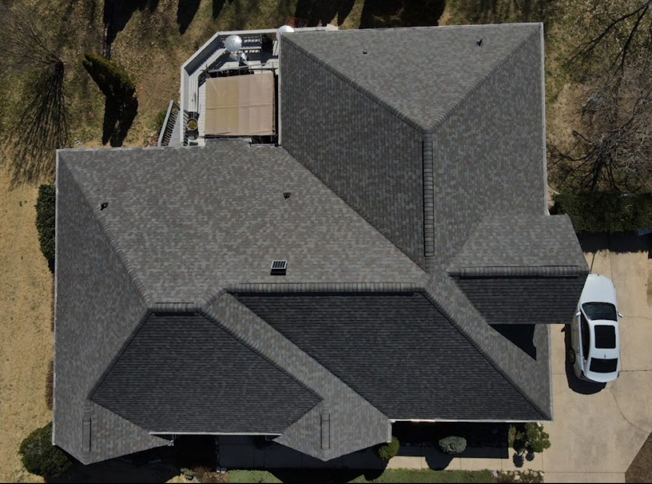Overhead drone view of a completed grey architectural shingle roof with new hip and ridge caps. Roofing work by Alba Pro Construction serving Paramus, NJ.