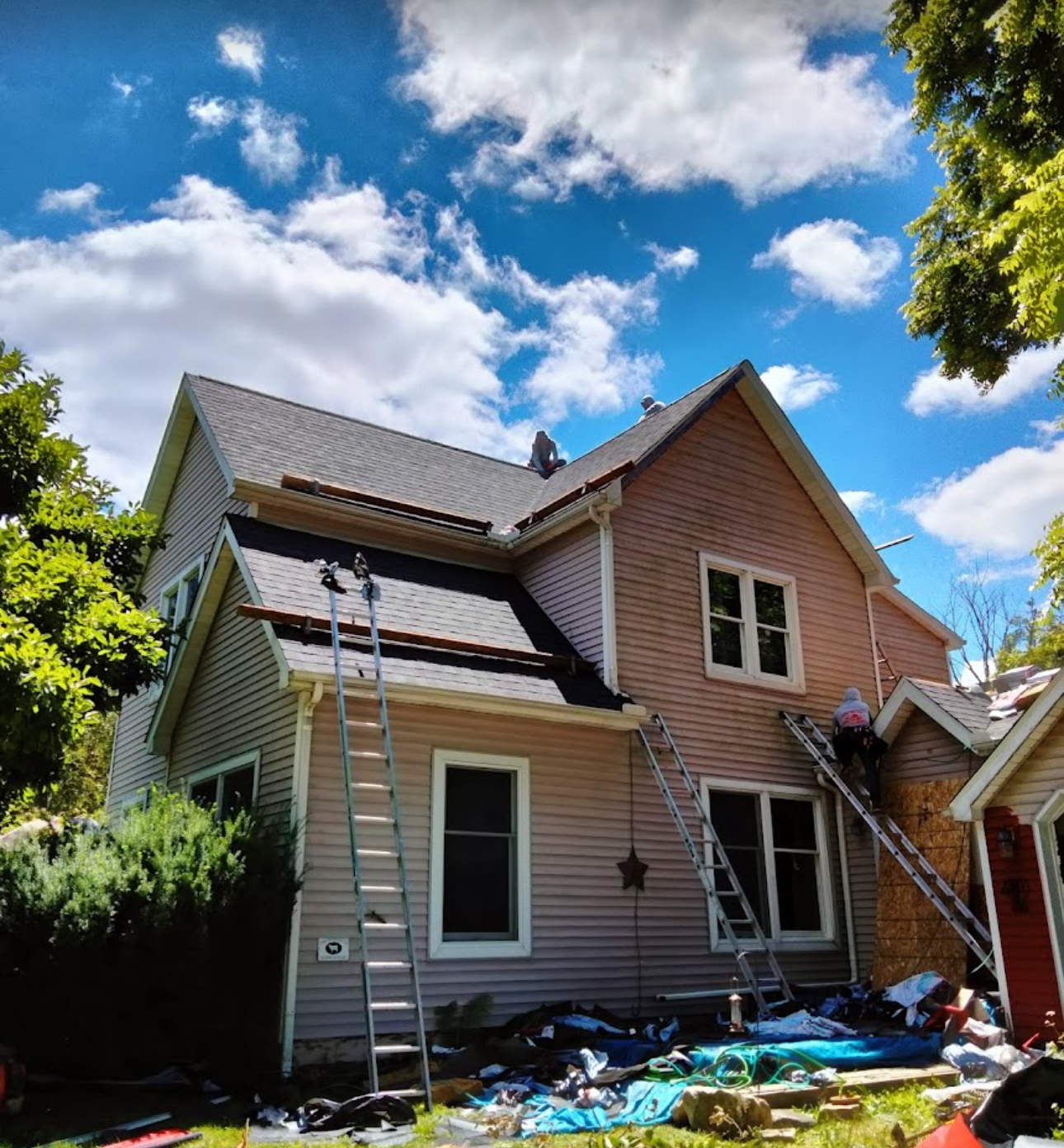 Two-story home with ladders set and old shingles stripped from the lower roof slopes during a replacement. Roofing work by Alba Pro Construction serving Hackensack, NJ.
