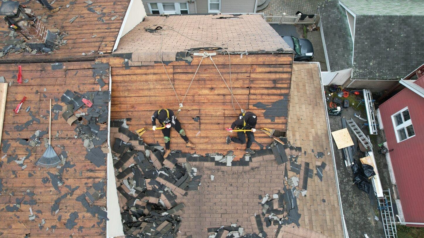 Roofing crew performing a controlled shingle tear-off with ground protection. Roofing work by Alba Pro Construction serving Elizabeth, NJ.