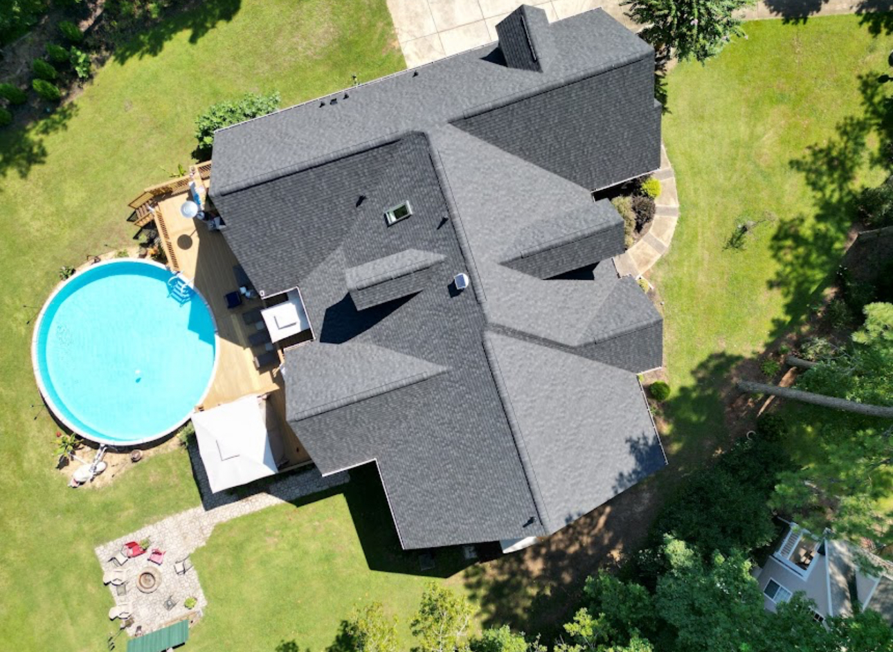 Aerial view of a completed grey shingle roof on a home with a pool and deck in the yard. Roofing work by Alba Pro Construction serving Paterson, NJ.