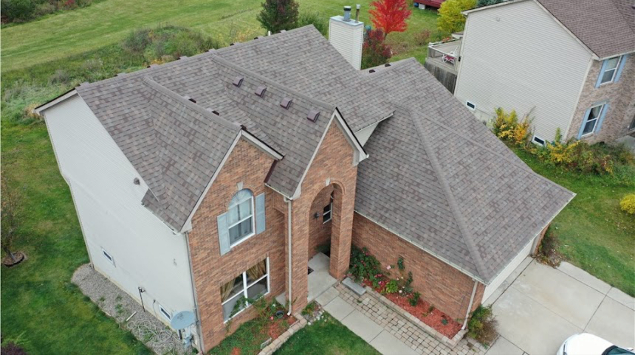 Aerial view of a brick two-story home with a completed weathered wood shingle roof and new ridge vents. Roofing work by Alba Pro Construction serving Hackensack, NJ.