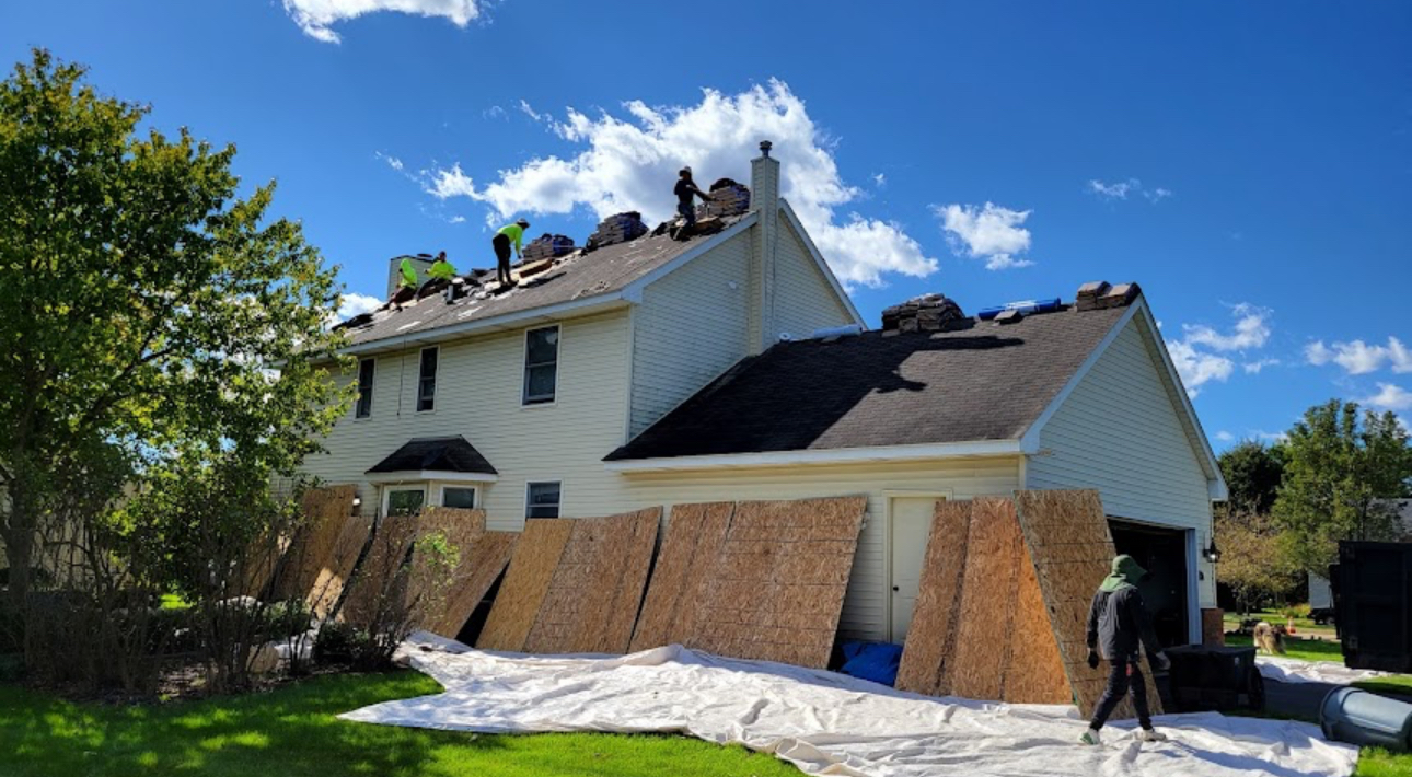Crew removing worn asphalt shingles from a colonial home with new bundles staged on the roof. Roofing work by Alba Pro Construction serving Passaic, NJ.