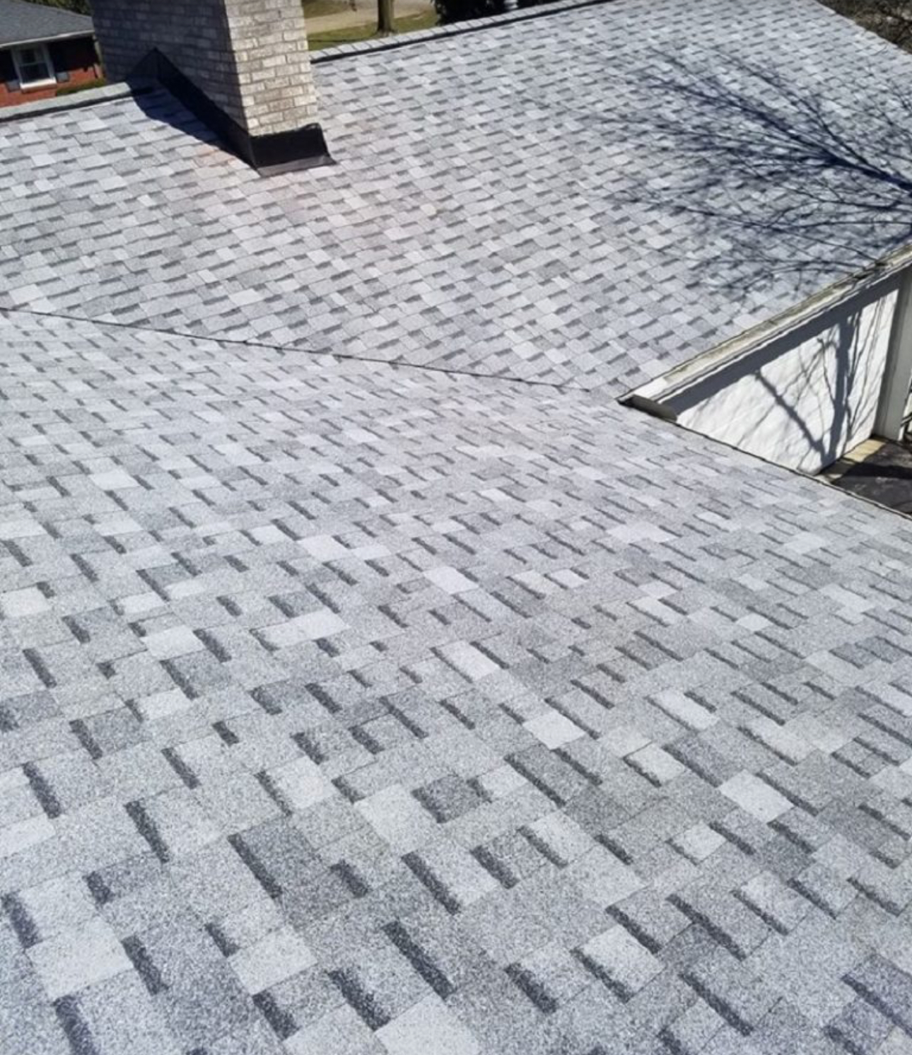 Close aerial view of a finished grey architectural asphalt shingle roof with new chimney flashing. Roofing work by Alba Pro Construction serving Garfield, NJ.