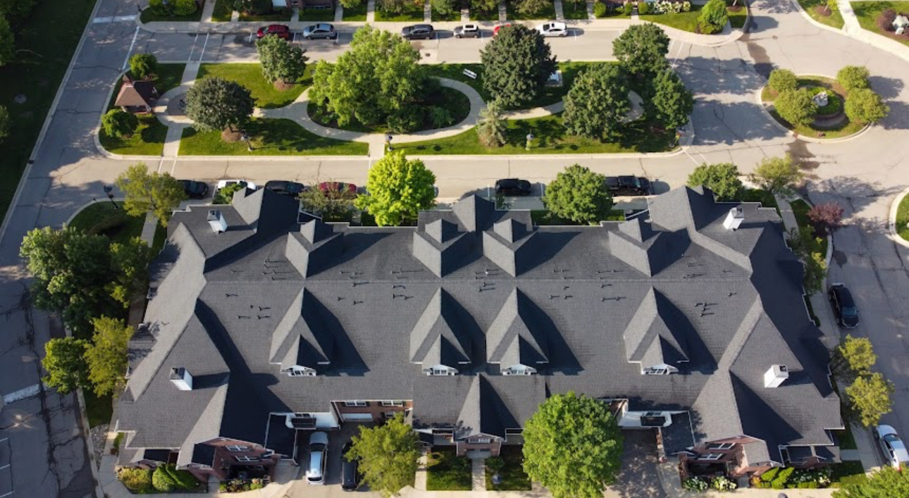 Aerial view of a townhome building with a completed dark grey architectural shingle roof. Roofing work by Alba Pro Construction serving Little Falls, NJ.