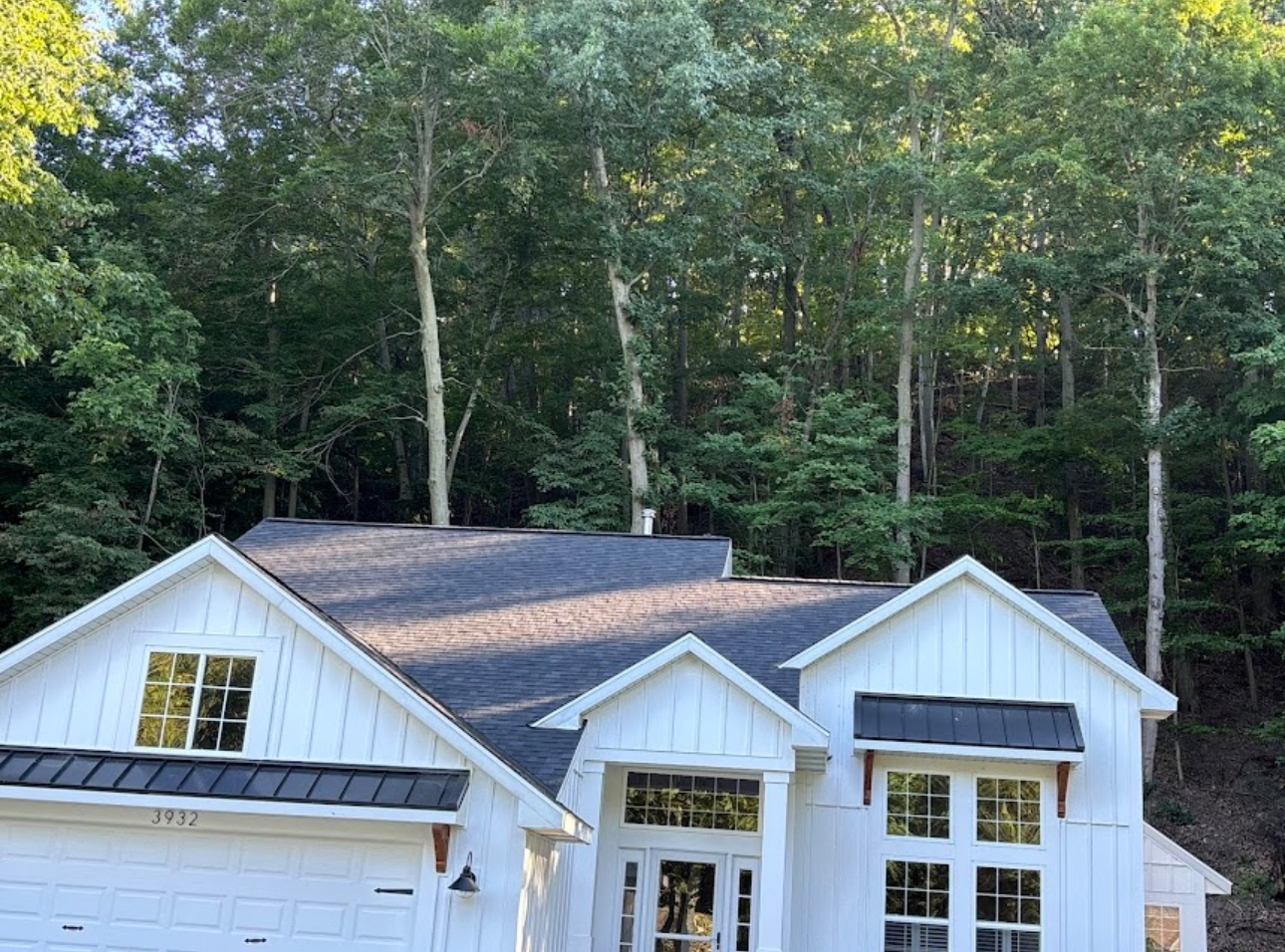White board and batten farmhouse with a completed dark architectural shingle roof and black metal accent roofs. Roofing work by Alba Pro Construction serving River Edge, NJ.