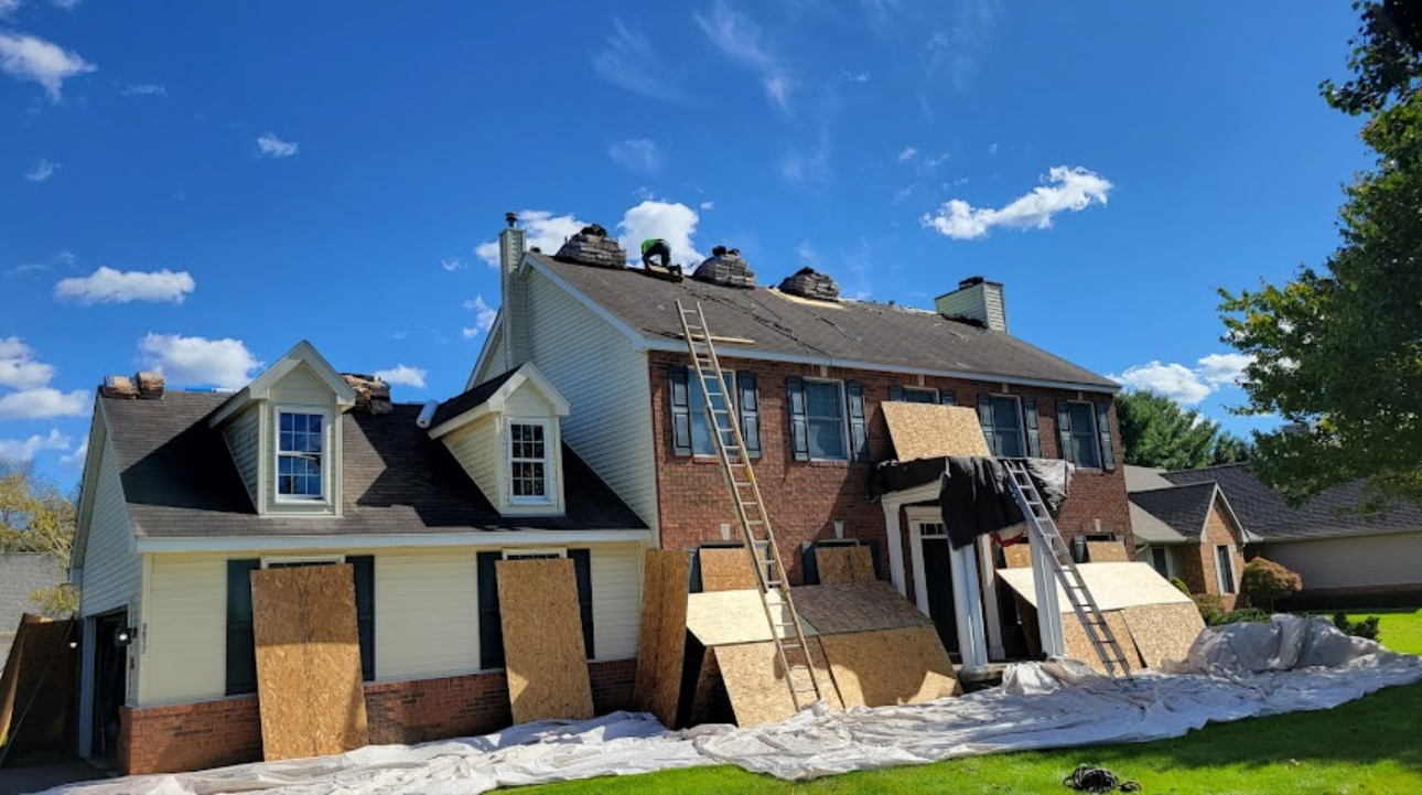 Roofing crew tearing off old shingles on a two-story home with plywood and tarps protecting the siding and landscaping. Roofing work by Alba Pro Construction serving Mahwah, NJ.