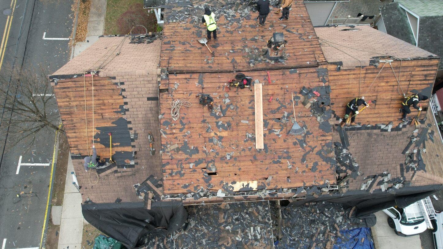 Roofing crew removing old asphalt shingles from a multi-slope roof in New Jersey. Roofing work by Alba Pro Construction serving Paramus, NJ.