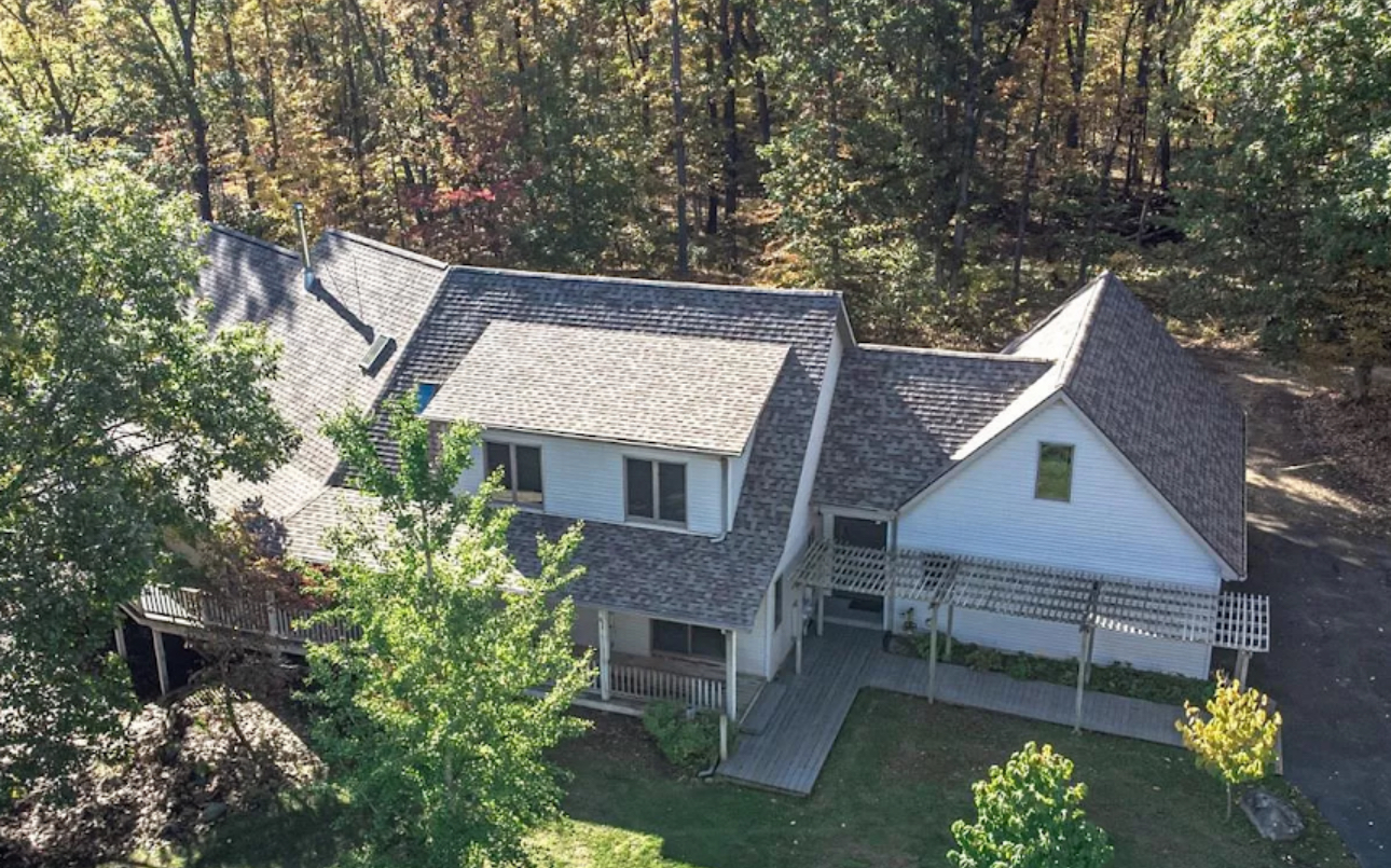 Aerial view of a completed asphalt shingle roof on a large wooded property home. Roofing work by Alba Pro Construction serving Franklin Lakes, NJ.