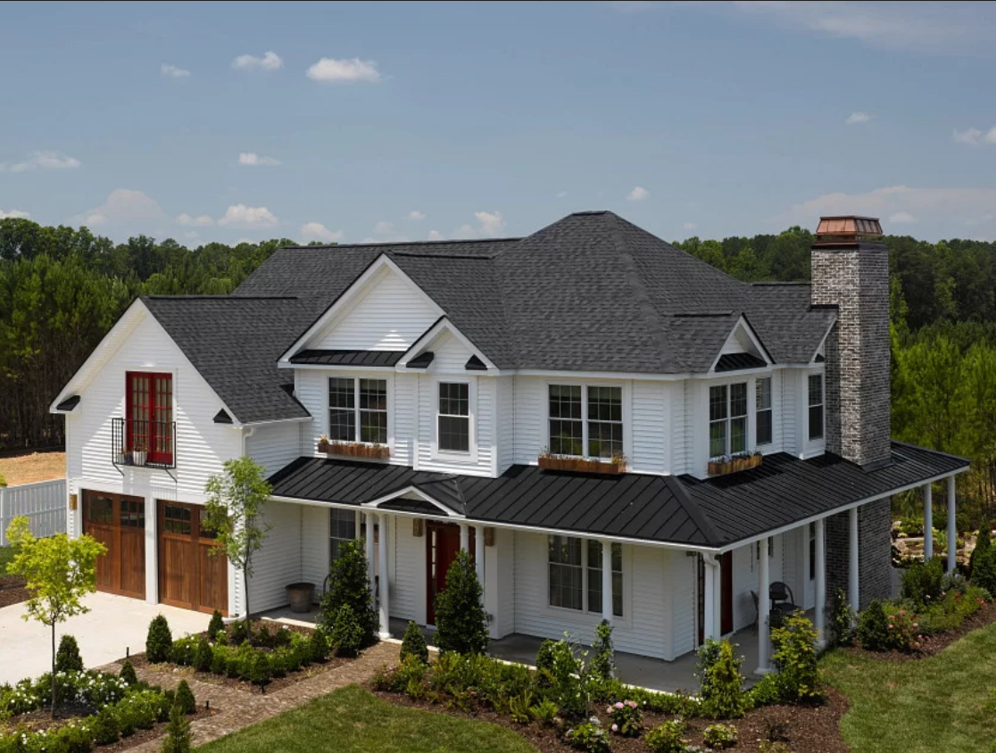 Completed architectural asphalt shingle roof with black standing seam metal porch roof on a white farmhouse. Roofing work by Alba Pro Construction serving Midland Park, NJ.