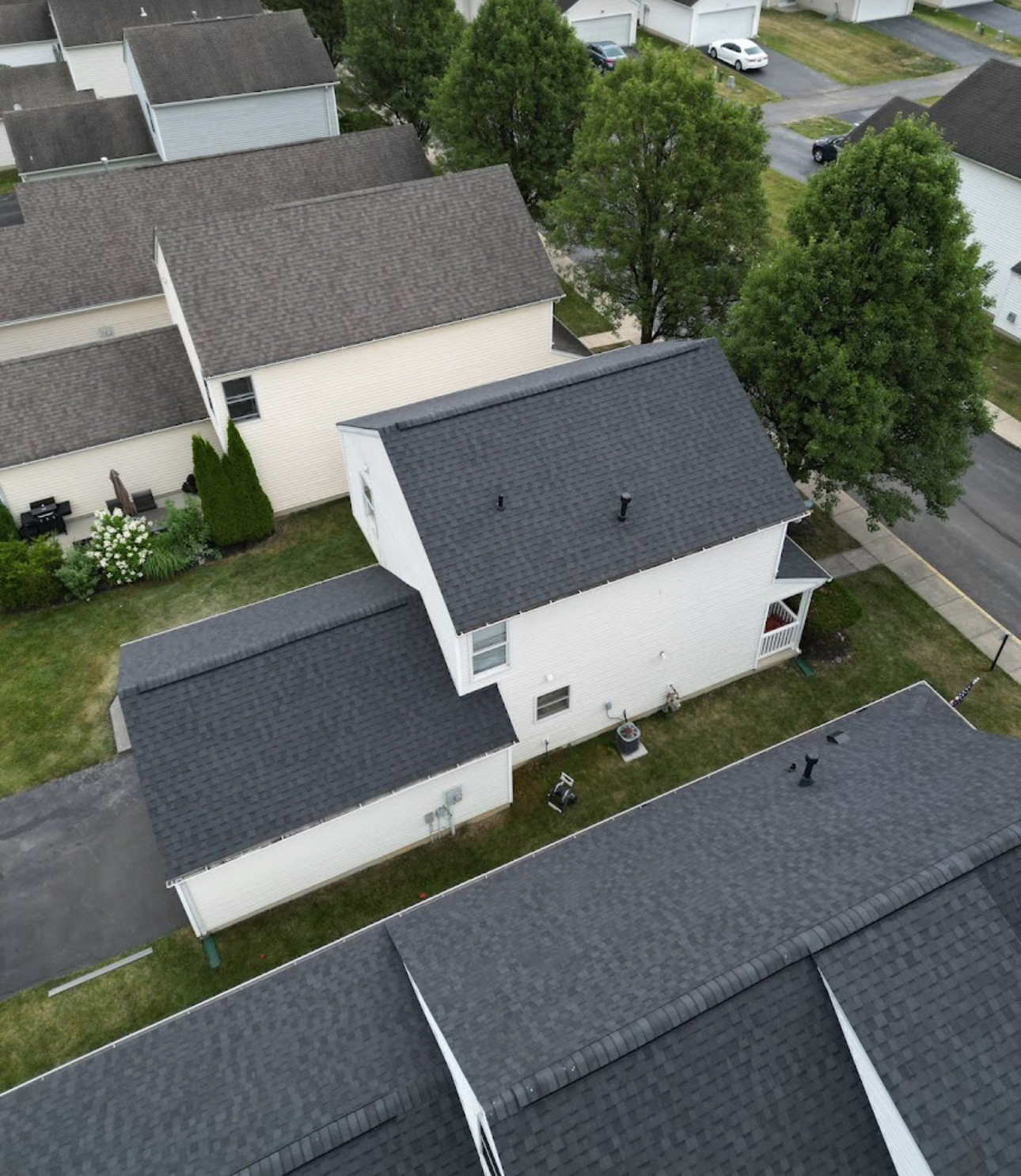 Aerial view of completed charcoal architectural shingle roofs on neighboring white homes. Roofing work by Alba Pro Construction serving Newark, NJ.
