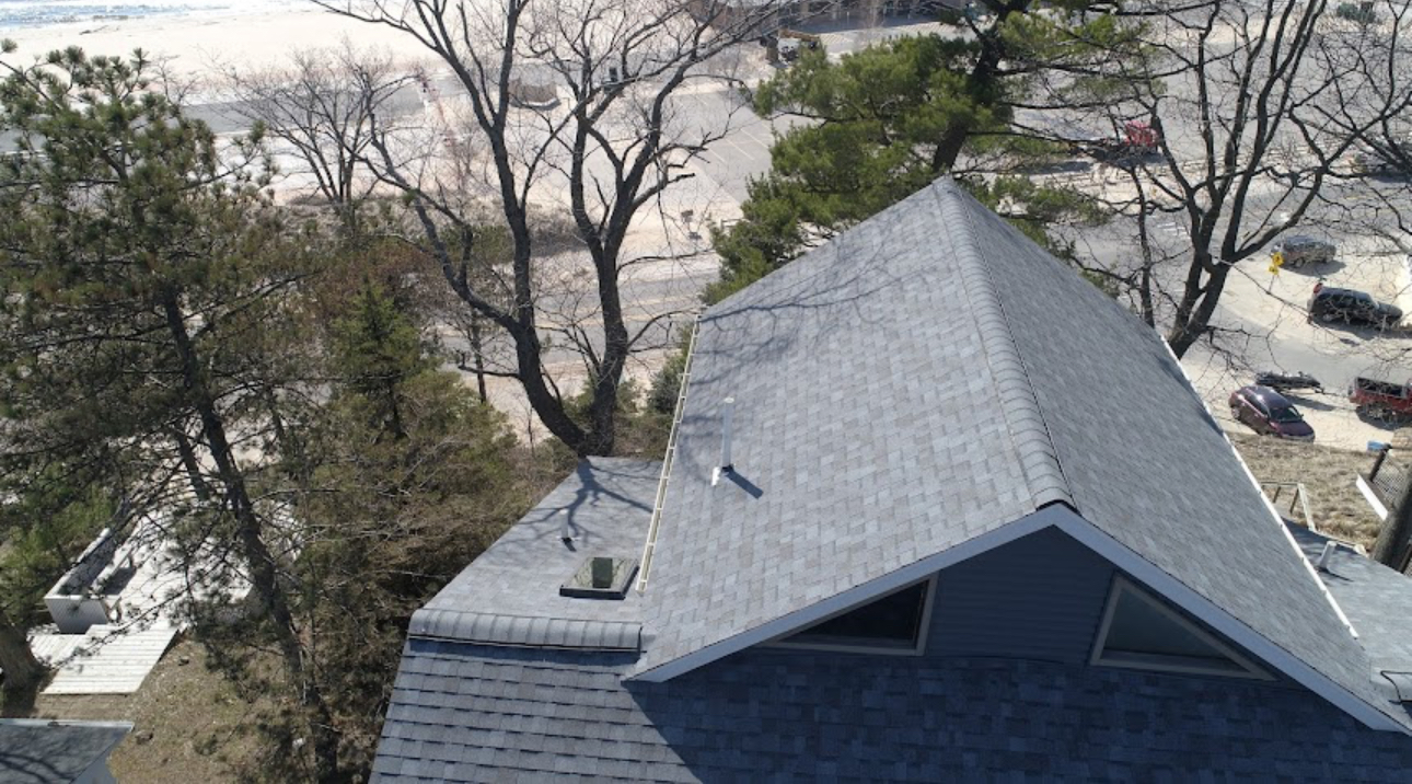 Aerial view of a finished light grey architectural shingle roof on a shore home. Roofing work by Alba Pro Construction serving Elizabeth, NJ.